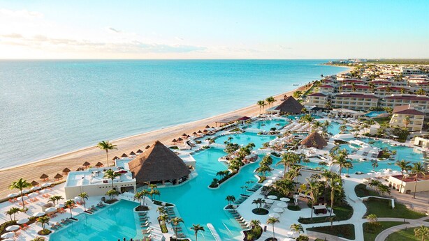 Un complejo turístico con una piscina grande, acceso a la playa y varias edificaciones.