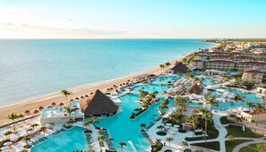 Un complejo turístico con una piscina grande, acceso a la playa y varias edificaciones.