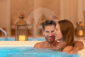 A couple in a hot tub with a blurred background.