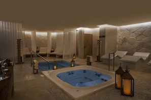 A spa area with a hot tub, lounge chairs, and candles.