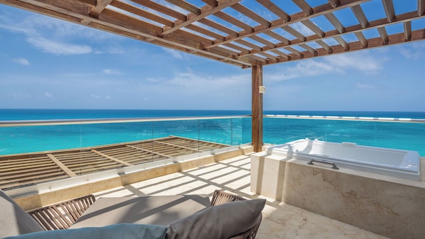 A balcony with a view of the ocean, a bathtub, and wicker furniture. - Sun Palace Cancun - Adults Only - All-inclusive (Cancun)
