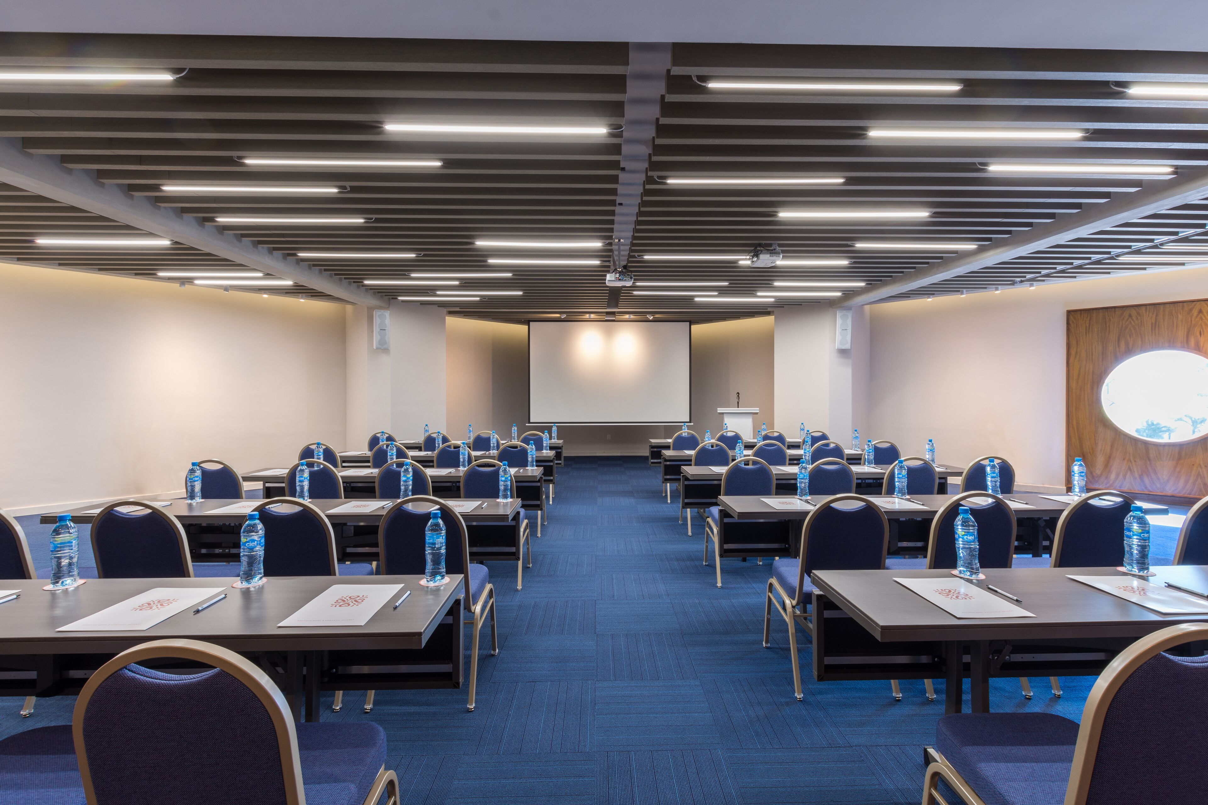 A conference room with rows of tables and chairs, equipped with water bottles and nameplates.