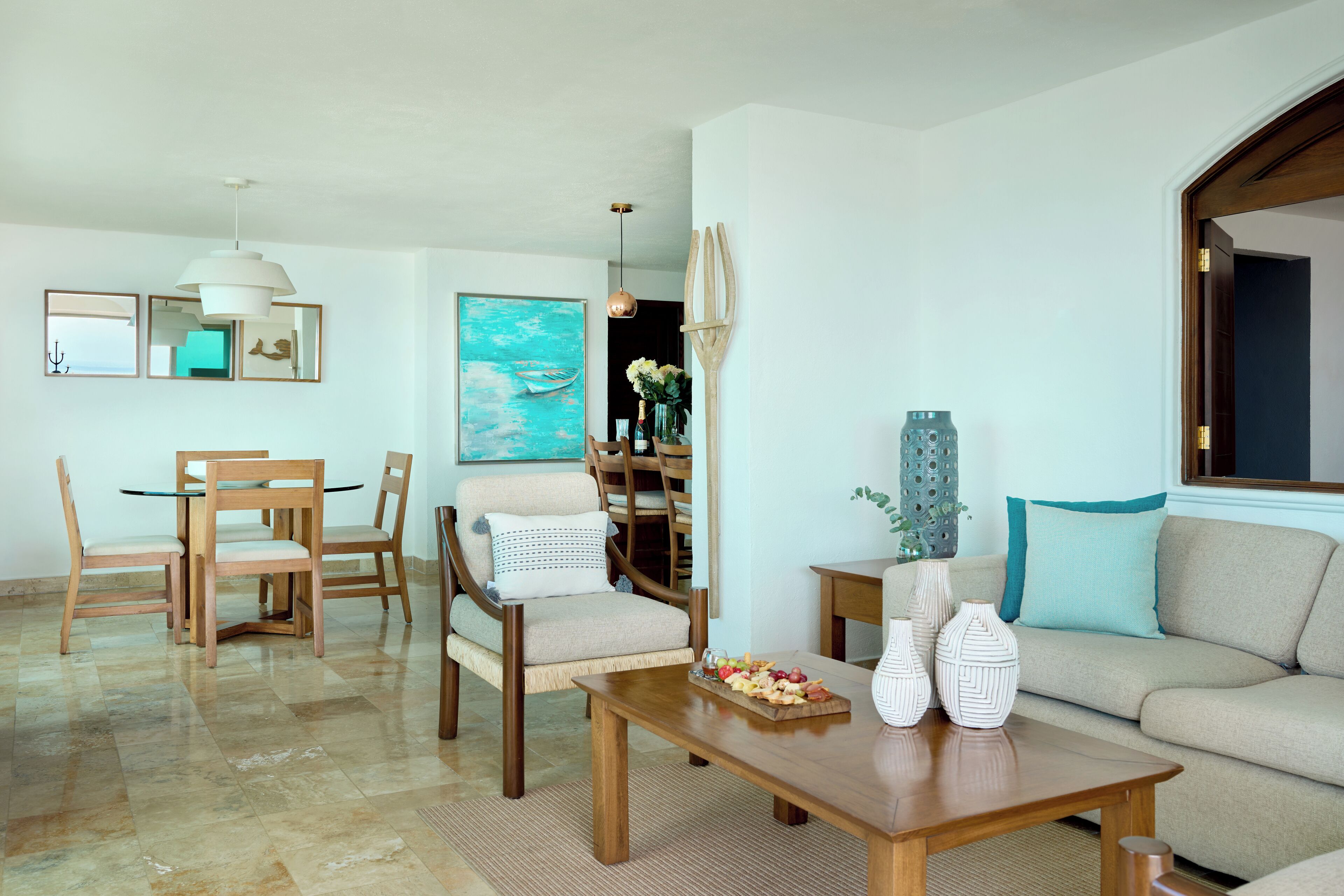 A modern living room with a wooden dining set, a sofa, and a coffee table with decorative items.