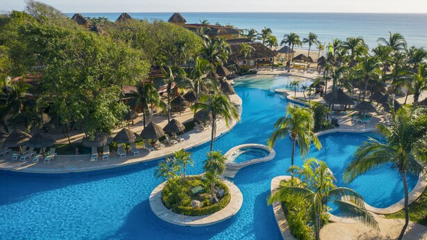 A resort with a large central pool, smaller satellite pools, and a beach area with thatched-roof huts. - Iberostar Waves Quetzal - All Inclusive (Playa del Carmen)