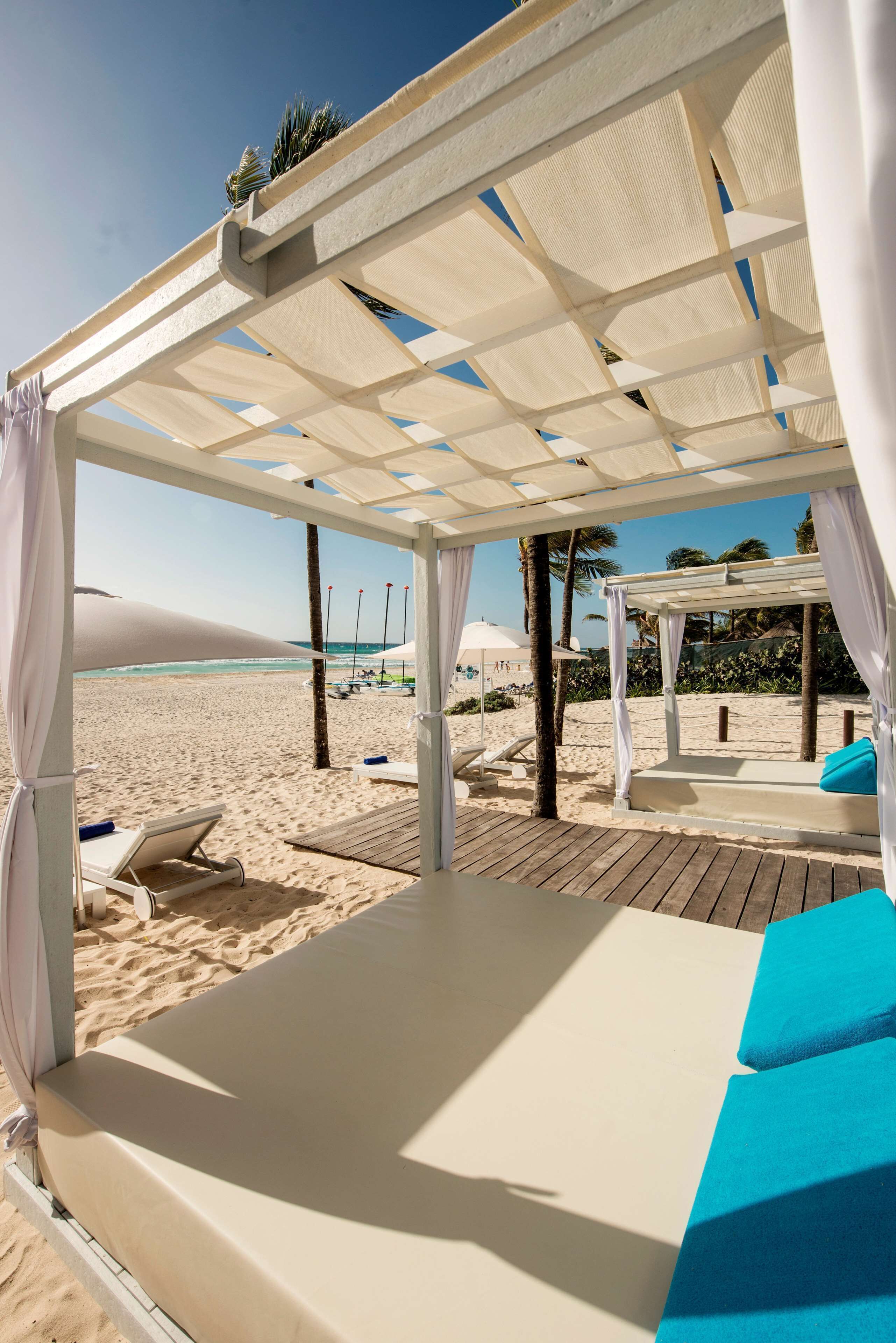 En la playa, playa de arena blanca, camastros y sombrillas 