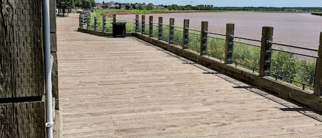 Una terraza de madera con barandilla metálica que da a un río.