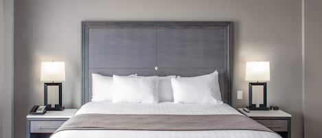 Habitación de hotel con una cama grande, dos mesitas de noche con lámparas, una mesita auxiliar y suelo de mármol.