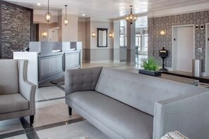 Relax in our inviting lobby, featuring a comfortable seating area, reception desk, and lush greenery.