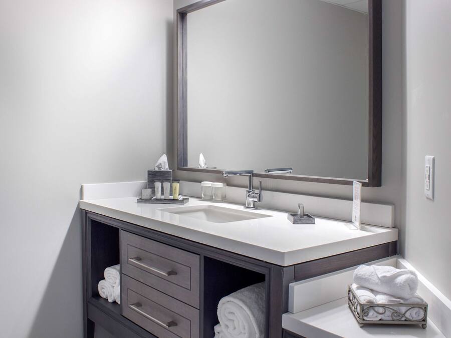 Un baño moderno con lavamanos doble, un espejo grande y un perchero para toallas.