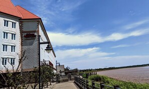 Classic hotel with a red roof and white brick facade, situated near a body of water.