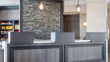 A reception desk with a stone wall backdrop, pendant lighting, and a shelf with snacks.
