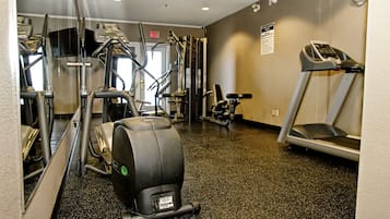 A gym with various exercise equipment including treadmills, elliptical machines, and weight machines.