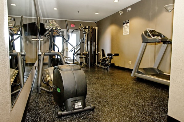 Un gimnasio con diversos equipos de ejercicio, incluyendo cintas de correr, elípticas y máquinas de pesas.