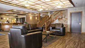 Un hall d’entrée avec des canapés en cuir, une table basse, un comptoir d’accueil et un escalier.