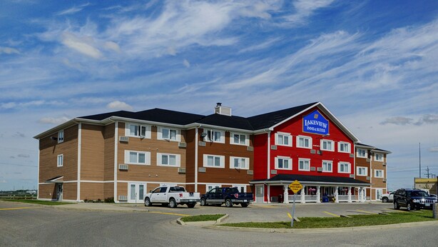 Un hôtel à plusieurs étages, à la façade rouge et marron, avec une enseigne indiquant « Lakeview Inns & Suites », et plusieurs véhicules stationnés devant.