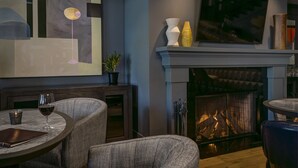 Una sala de estar moderna con chimenea, asientos cómodos y un cuadro abstracto grande en la pared.