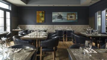 A restaurant with a modern interior, featuring a mix of booth and table seating, with artwork on the walls.