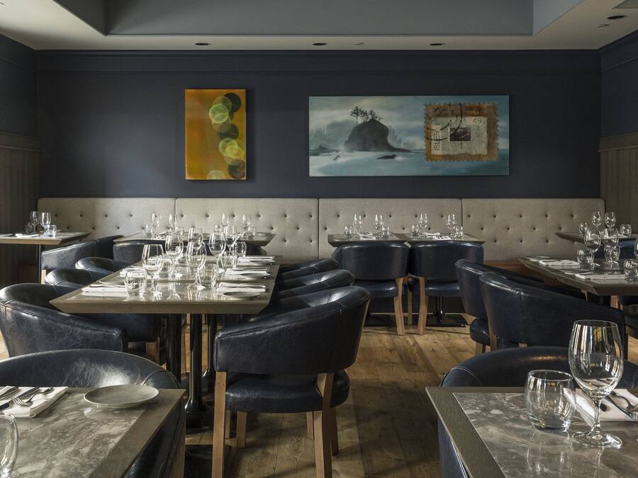 Un restaurant au décor moderne, proposant un mélange de banquettes et de tables, et dont les murs sont ornés d’œuvres d’art.