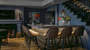 Una cocina moderna con barra, taburetes de bar, chimenea y escalera.