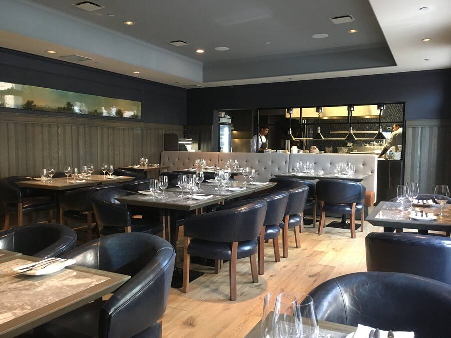 Un restaurante con mesas preparadas para comer, una zona de bar y vistas a la ciudad.