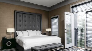 Un dormitorio moderno con una cama grande, dos mesitas de noche, un banco y una puerta que da a un balcón.