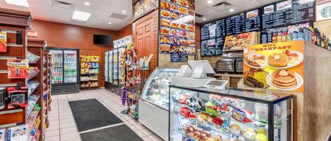Een foodcourt met diverse eetgelegenheden, een vitrine met pluchen speelgoed en een menubord boven de balie.