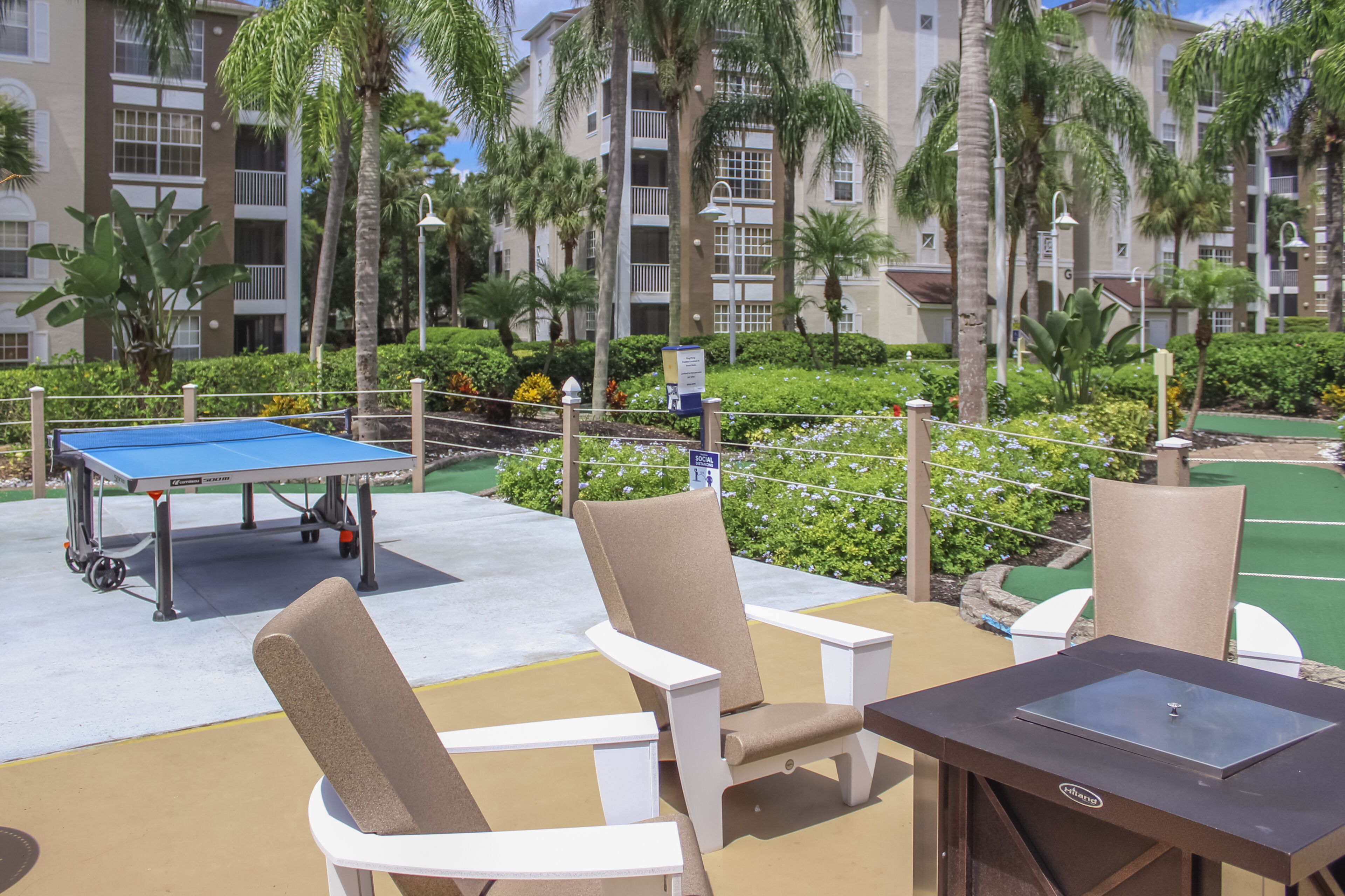 A poolside area with a ping pong table, lounge chairs, and a grill.