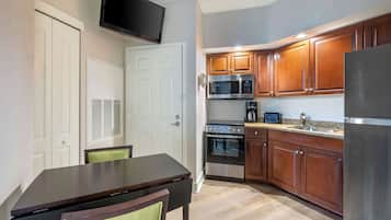 A compact kitchen with wooden cabinets, a microwave, an oven, and a refrigerator.