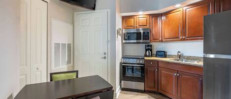 A compact kitchen with wooden cabinets, a microwave, an oven, and a refrigerator.