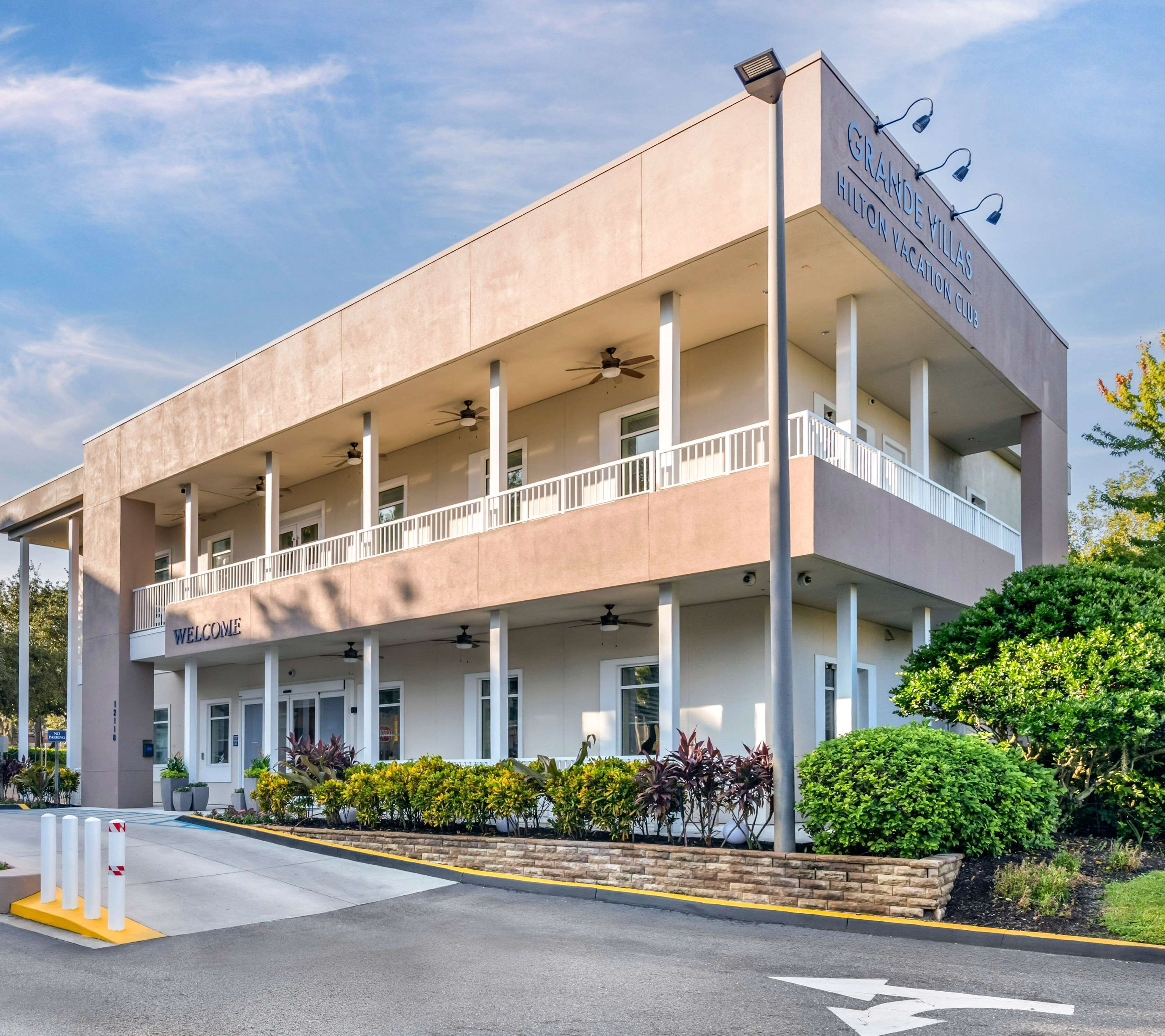 A two-story hotel with a 'Welcome' sign at the entrance, multiple balconies, and a 'Grande Villas' sign indicating a vacation club.