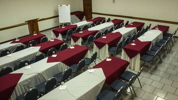 Un salón de conferencias con filas de mesas y sillas, una pizarra y un atril.