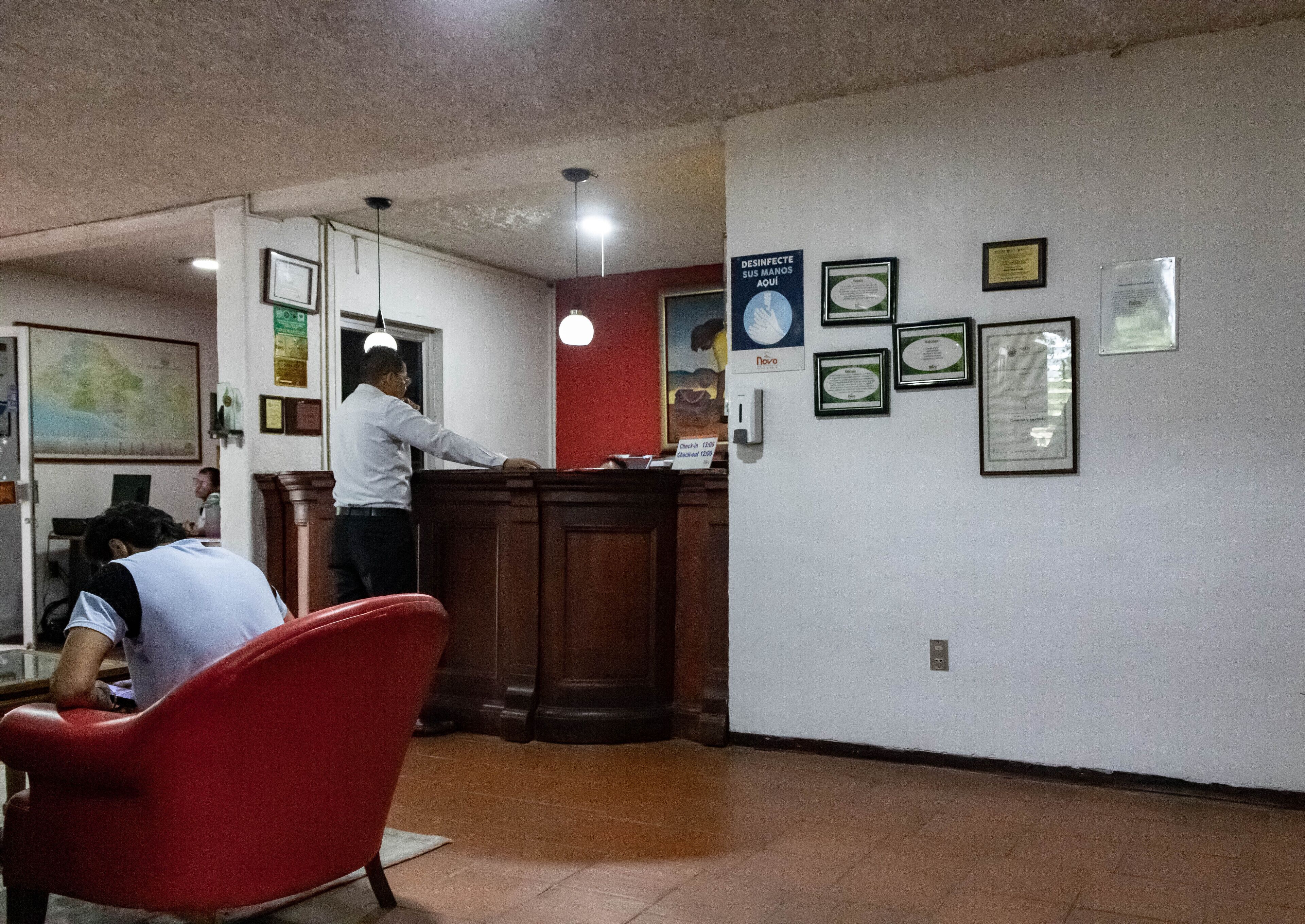 Zona de recepción con un mostrador, sillas y certificados enmarcados en la pared.
