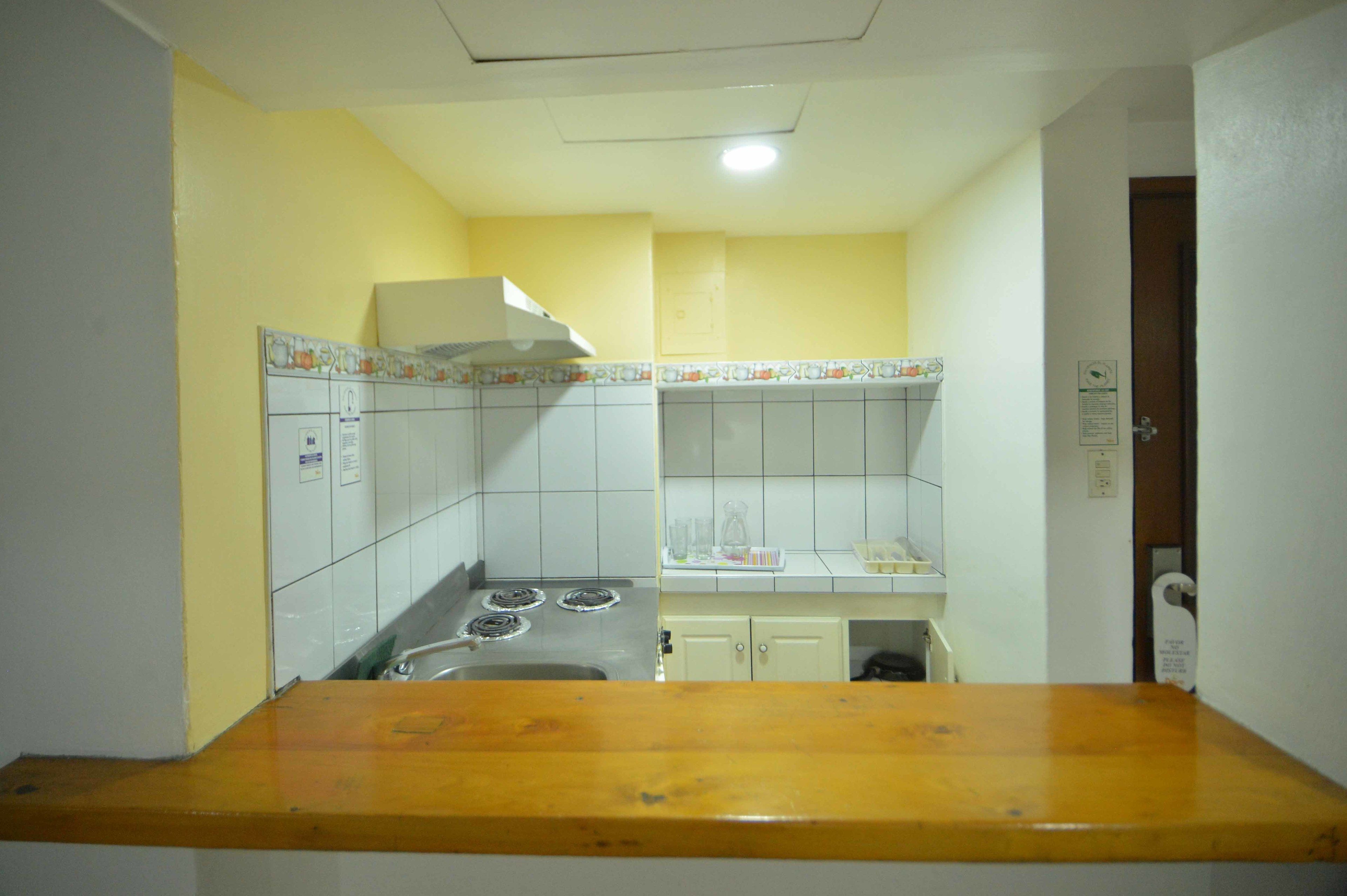 Una cocina con armarios blancos, una estufa y una encimera de madera.