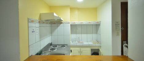Una cocina con armarios blancos, una estufa y una encimera de madera.