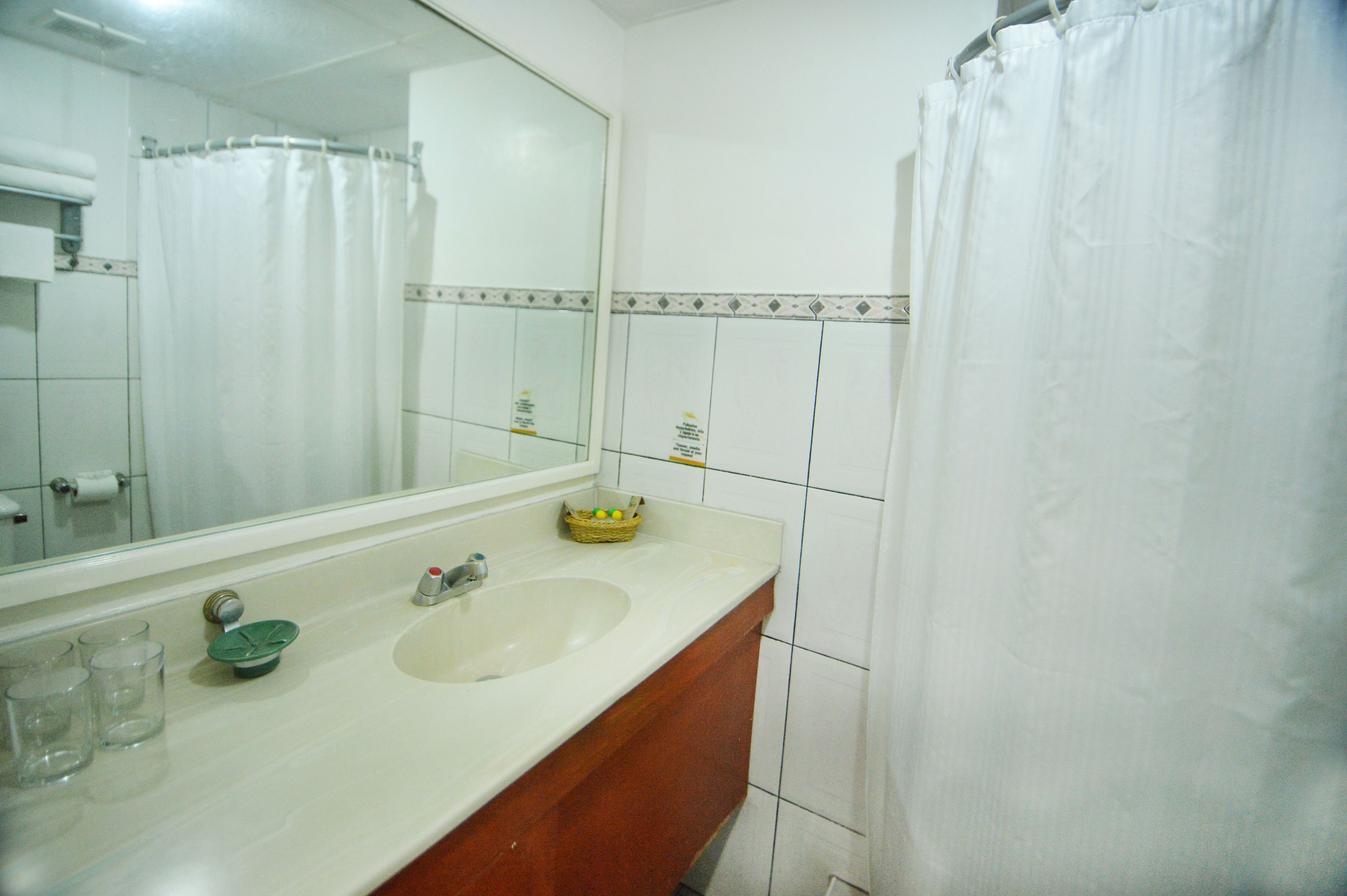 Une salle de bain avec un lavabo blanc, un miroir et des murs carrelés.