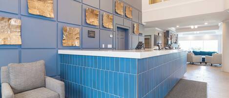A modern kitchen with blue tiles, a bar area, and a seating area with a gray armchair.