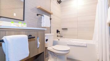 A modern bathroom with a toilet, bathtub, and a wooden vanity with a towel rack.