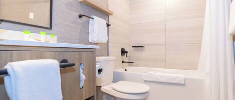 Un baño moderno con inodoro, bañera y tocador de madera con perchero.