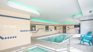 An indoor swimming pool with tiled walls and a blue chair area. - Sandman Hotel Quesnel (Quesnel)