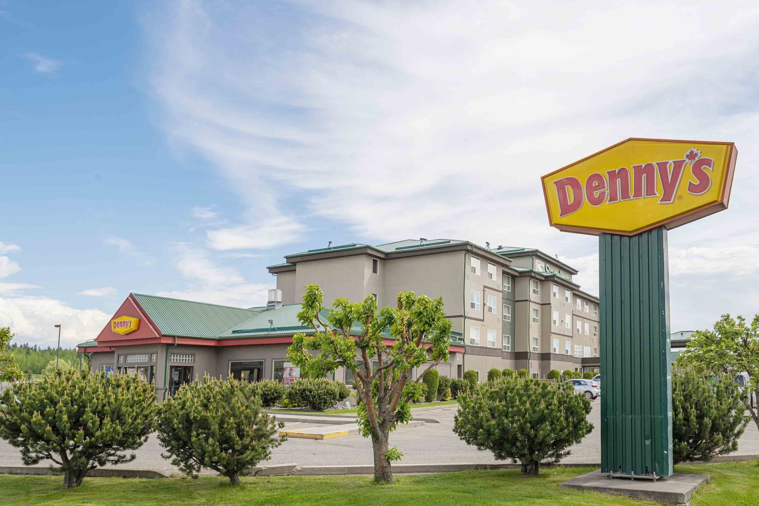 A Denny's restaurant with a green sign, surrounded by trees and a parking lot.