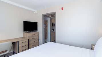 Ett hotellrum med en säng, ett skrivbord med en tv, en stol och en garderob.
