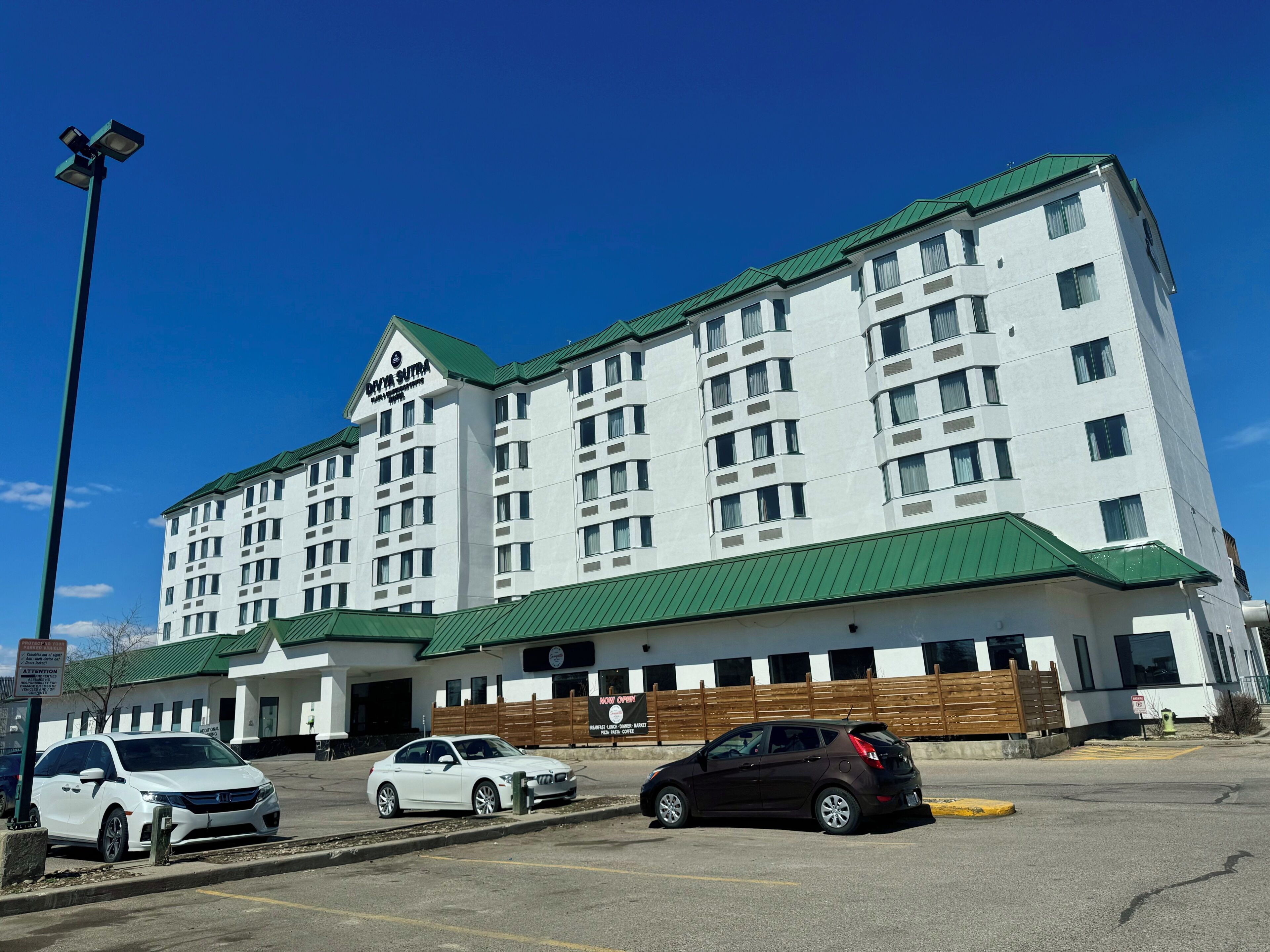 A multi-story hotel with a green roof and white exterior walls.