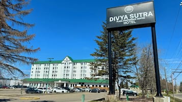 Une enseigne indiquant le centre de conférences et l’hôtel Divya Sutra Plaza, avec un parking situé devant.