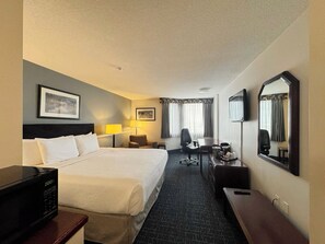 A hotel room with a bed, a desk, a chair, a TV, and a mirror. - Divya Sutra Plaza and Conference Centre Calgary Airport (Calgary)