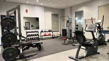 Un gimnasio con equipamiento de levantamiento de pesas, máquinas de cardio y mancuernas.