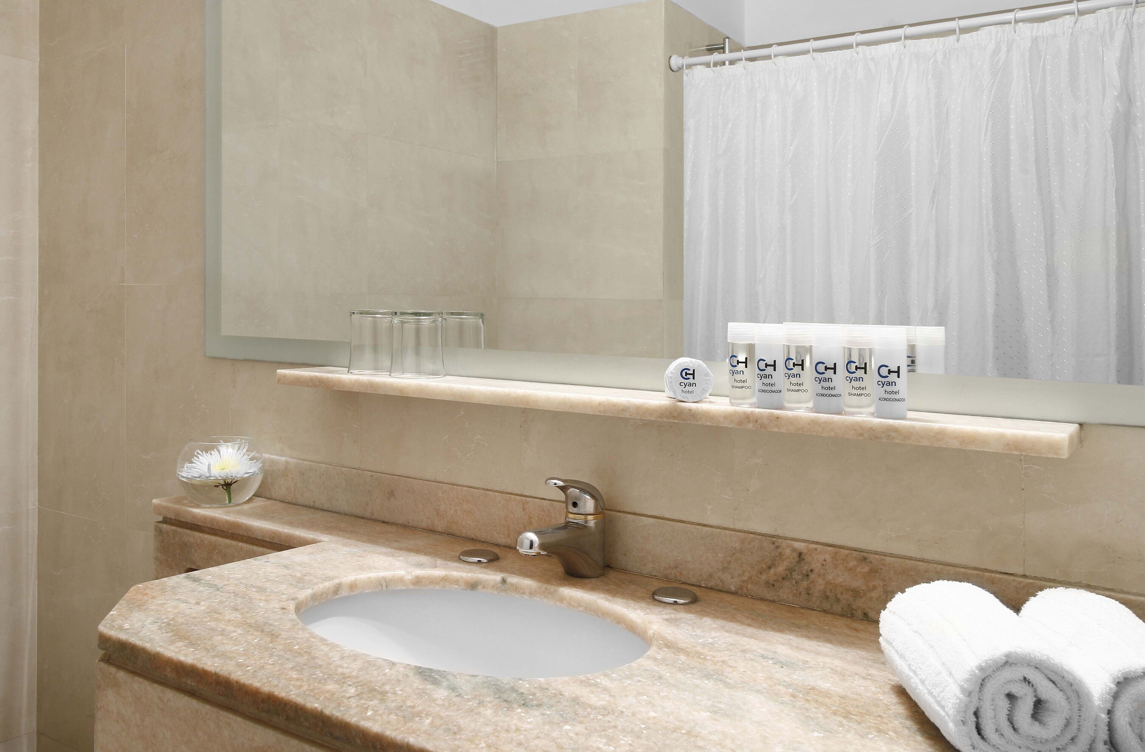 A bathroom with a marble sink, a mirror, a towel rack, and a shelf with toiletries.