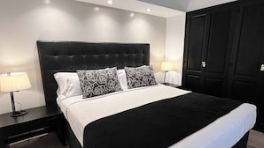 Un lit bien fait, avec une tête de lit noire, deux lampes de chevet et une armoire noire.