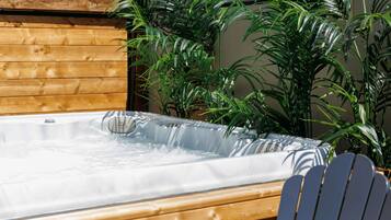 A hot tub with a wooden deck and surrounding greenery.