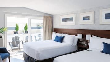 A hotel room with two beds, a balcony with outdoor seating, and framed pictures on the wall.