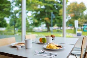 A breakfast table with plates of food, a coffee cup, and utensils.
